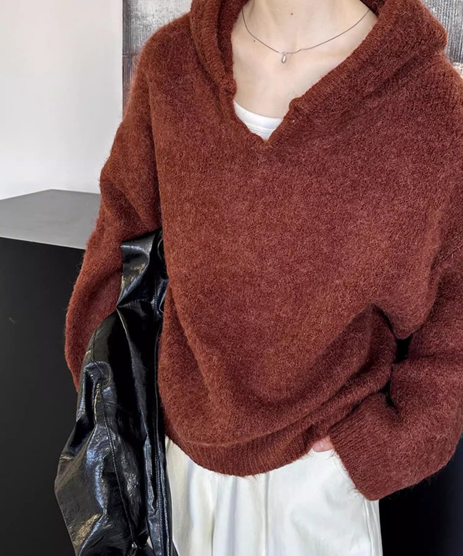 ブラウンのVネックフーディニットに、白のワイドパンツを合わせ、黒のバッグを持つ女性のショット。