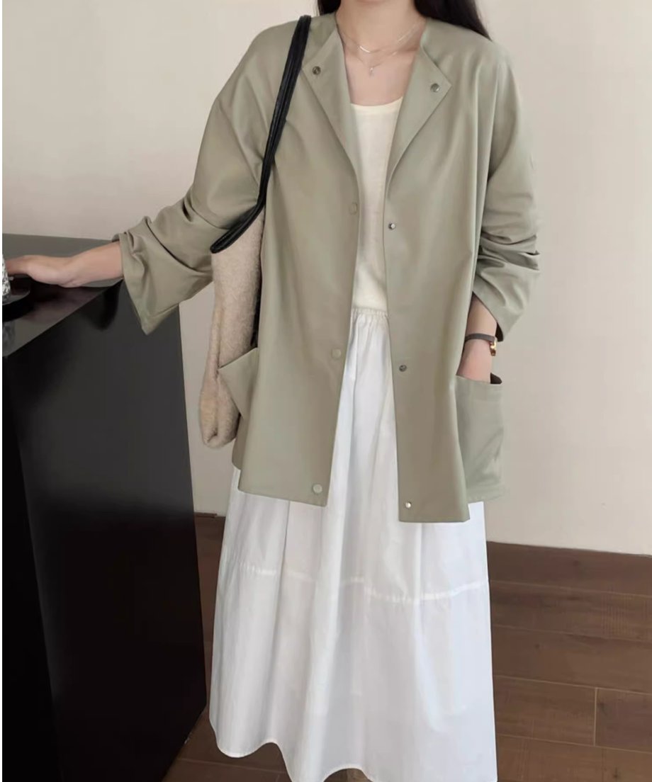 カーキグリーンのノーカラーショートコートと白のインナー、白のロングスカートを合わせた女性の着画。