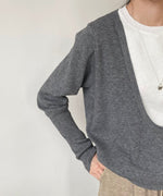グレーのワイドネックフェイクレイヤードニットと白のインナーを着用した女性のバストアップ。
