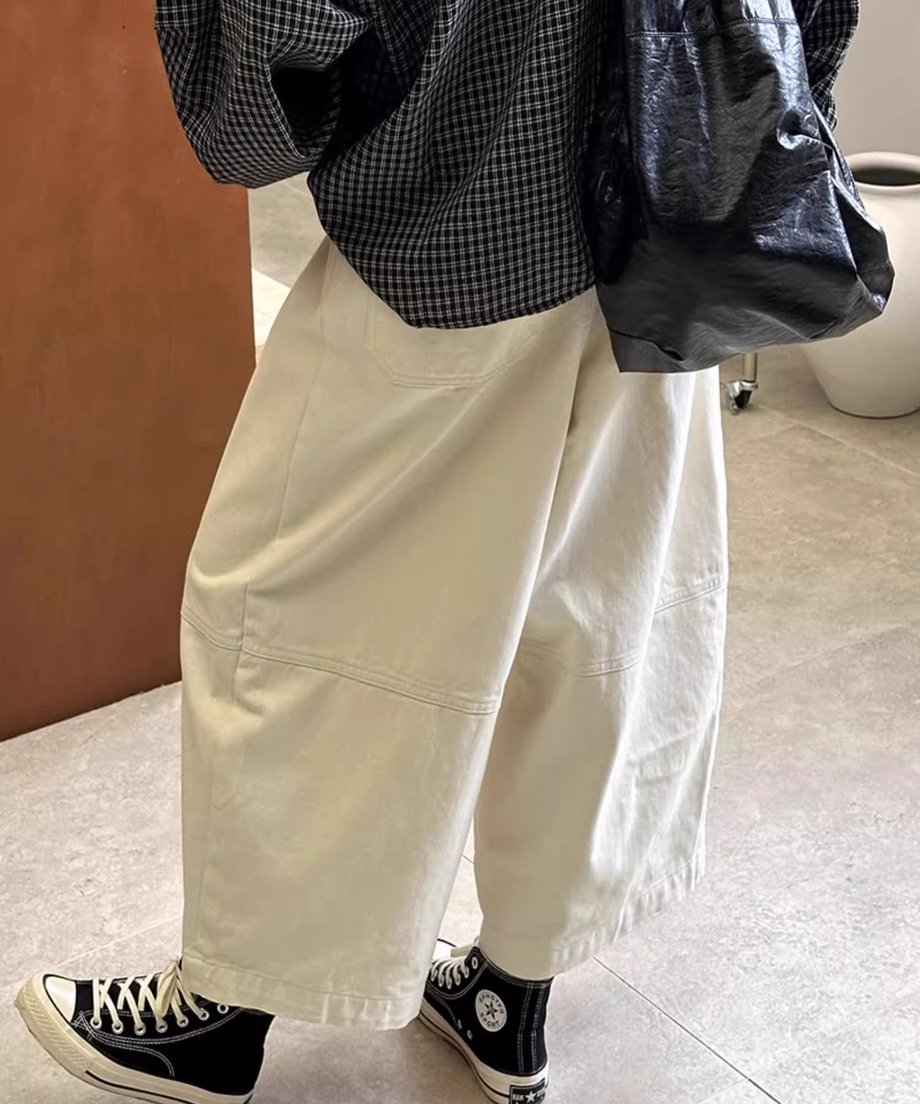 オフホワイトのワイドパンツの後ろ側の着用画像。ゆったりしたシルエットと膝の切り替えディテールが確認できる。