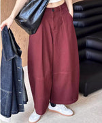 ボルドーのワイドパンツと白スニーカーの着用画像。デニムジャケットと大きな黒のバッグを合わせている。
