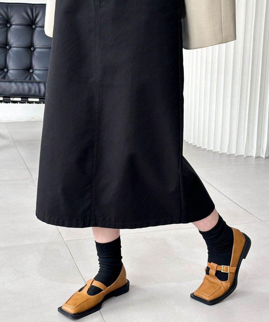 黒いミディ丈スカートに黒いソックスと茶色のメリージェーンシューズを合わせた足元のクローズアップ。