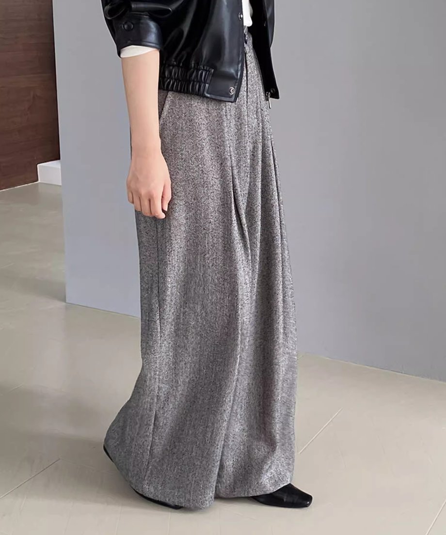 白いインナーに黒いレザージャケットを羽織り、ライトグレーのワイドレッグパンツを着用した女性の側面からのコーディネート。
