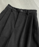 黒の太畝コーデュロイ膝丈ワイドパンツのウエスト部分のディテール、フロントボタンとタック、ジップフライのクローズアップ。