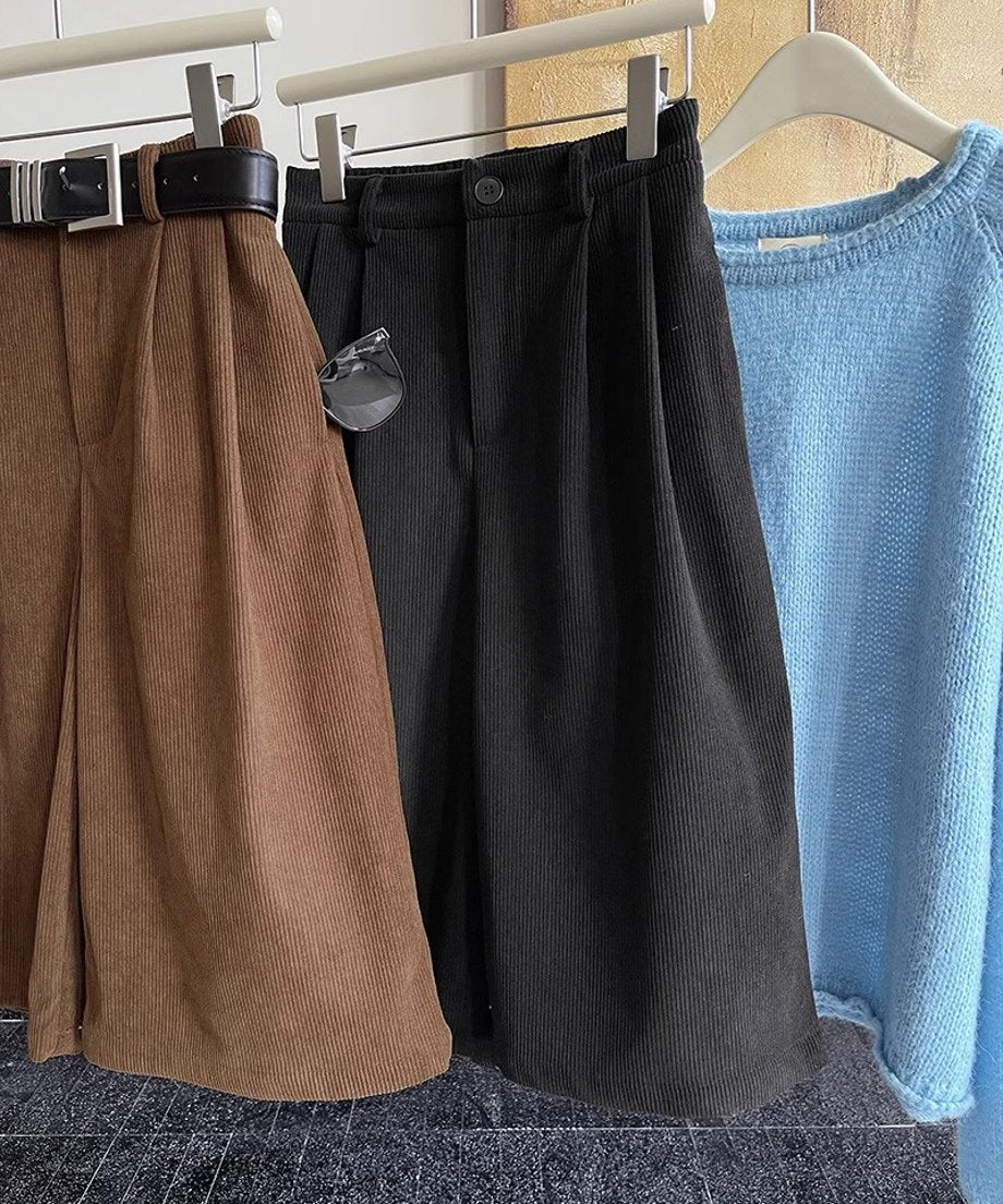 茶色（ベルト付き）と黒の太畝コーデュロイ膝丈ワイドパンツ、および水色のニットがハンガーにかけられた商品全体の様子。