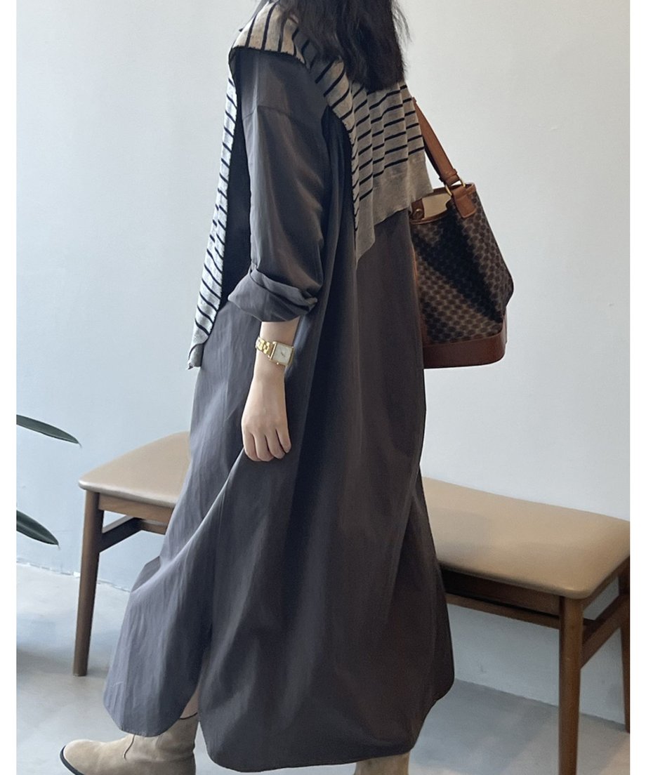 ダークグレーのロングシャツワンピースを着用した女性の斜め後ろからのショット。ブラウン系のバッグとボーダーニットがアクセントになっている。