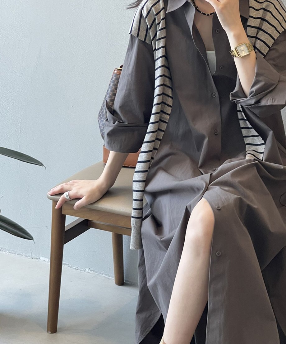 ダークグレーのロングシャツワンピースを着用した女性が椅子に座っている画像の接写画像。