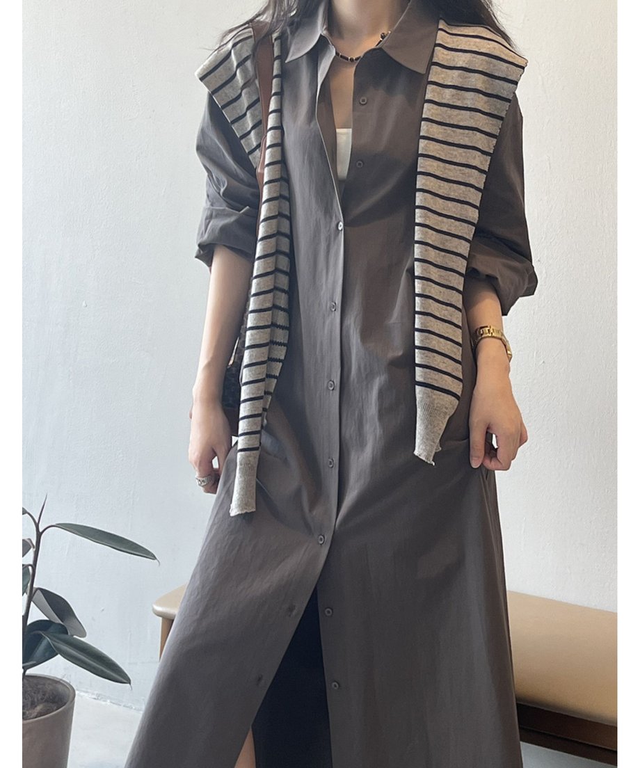 ダークグレーのロングシャツワンピースを着用した女性。インナーの白とストライプ柄のニットがアクセントになっている。
