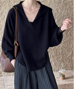 黒のセーラーカラーVネックニットにストライプ柄のワイドパンツを合わせ、茶色のショルダーバッグを持った上半身のコーディネート。
