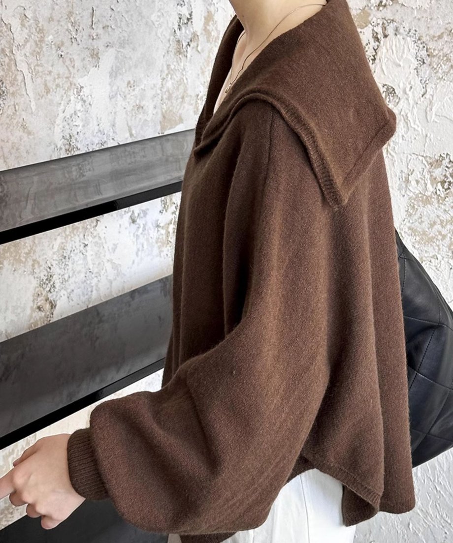 ブラウンのセーラーカラーVネックニットを横から捉えたクローズアップ。セーラーカラーの立ち上がりと、白いボトムスとのコントラストが見える。