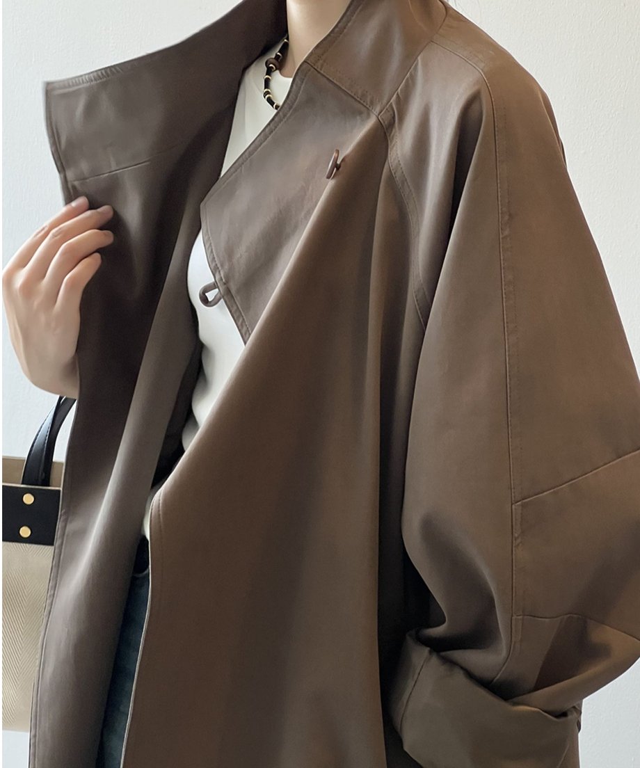コーヒー色のミドル丈コートのアップ。白いTシャツをインナーに、コートの襟と肩周りのデザインが見えるクローズアップ。