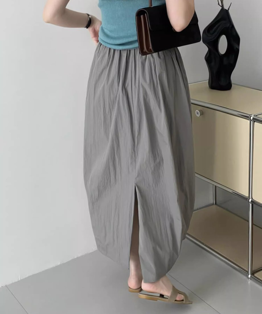 グレーのロングバドスカートの後ろ中央にスリットが入ったデザイン。ターコイズブルーのトップスを合わせた女性の後ろ姿。