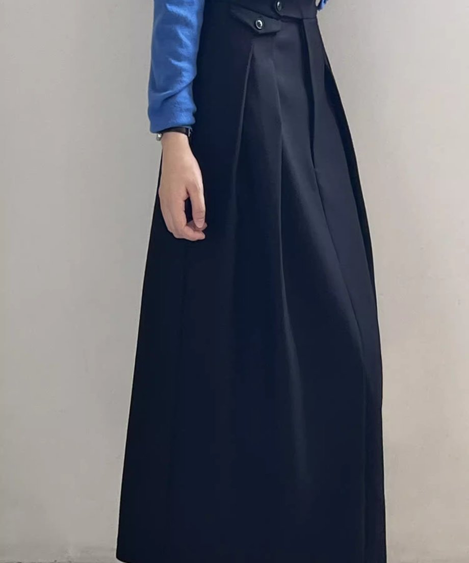黒のストレートロングタックスカートを着用した側面からの画像。タックのドレープ感がみえる。