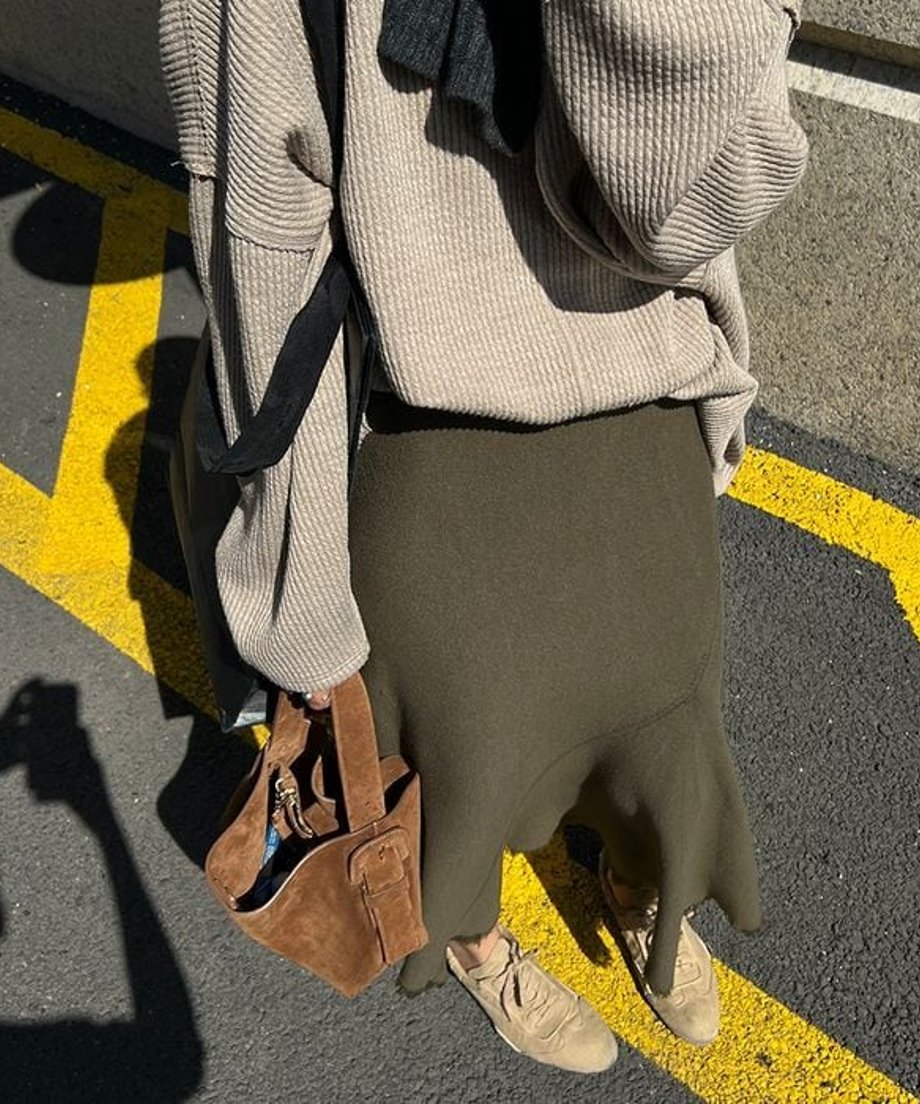 armyグリーンのニットマーメイドスカート。ベージュ系のニットとスニーカーを合わせて着用している女性の、屋外での全身。