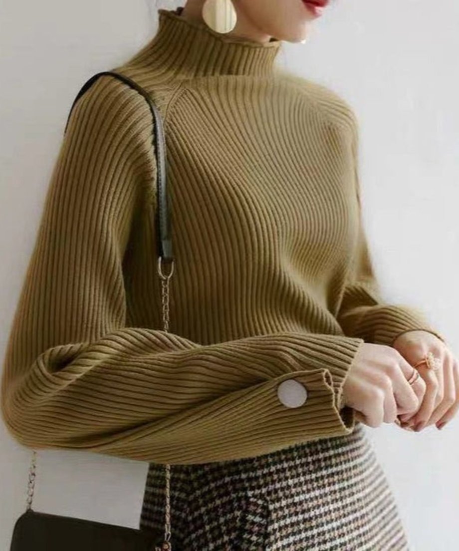 カーキ色の細リブハイネックニットとデニムを着用し、ショルダーバッグをかけた女性の全身画像。