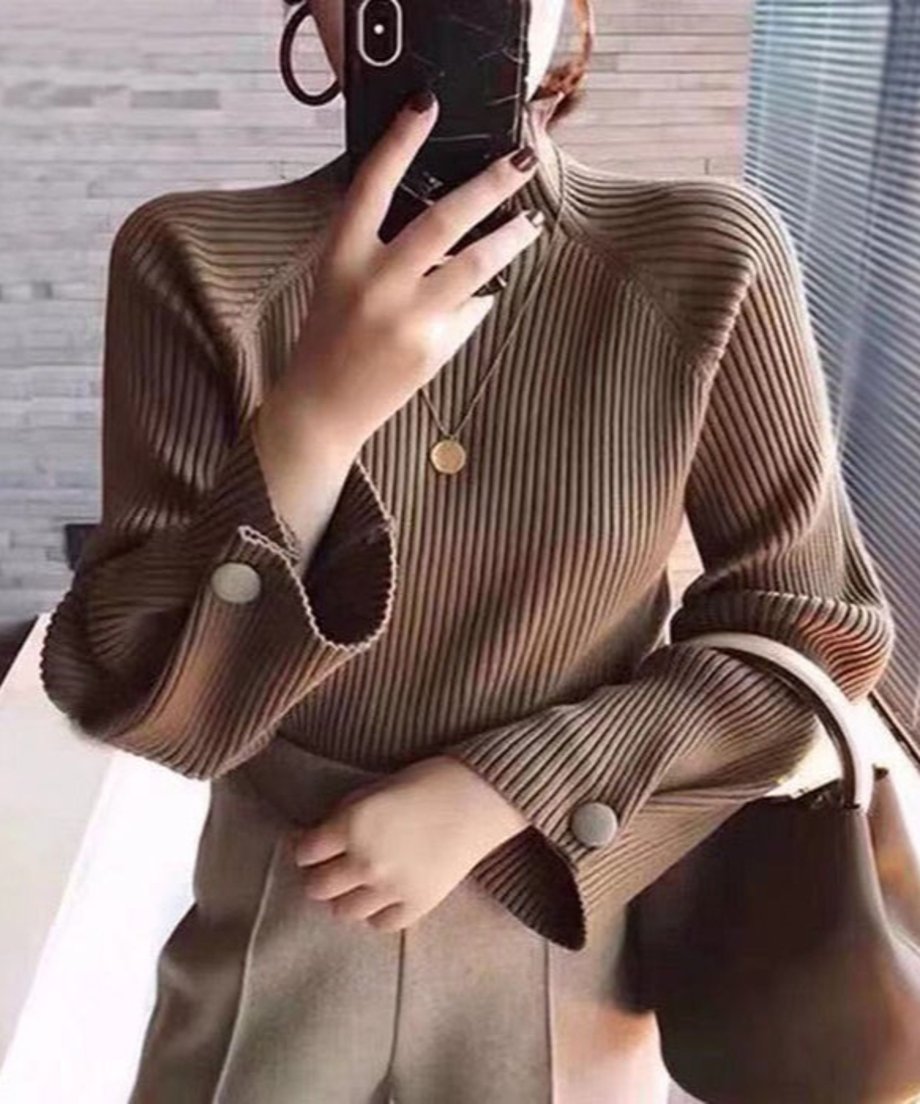 ブラウン色の細リブハイネックニットとブラウン系のトラウザーを着用した女性のクローズアップ画像。