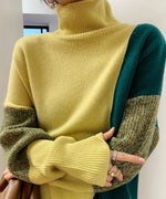 明るいイエローグリーンと濃いグリーンの配色切り替えが特徴的なハイネックニットを着用した女性のアップ。