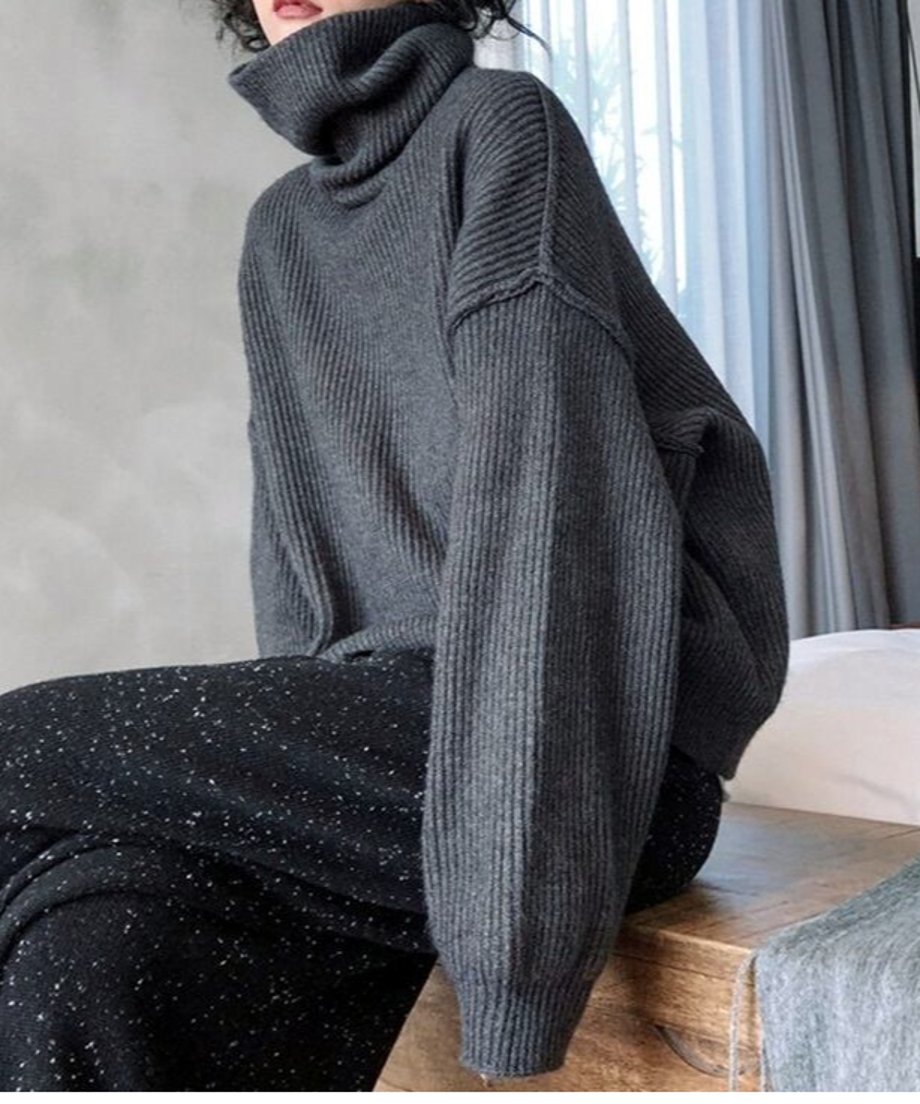 グレーのリブ編みオーバーサイズハイネックニットを着用した女性の全身画像。