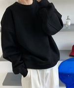 ブラックのオーバーサイズスウェットと白のワイドパンツを合わせた女性のクローズアップ。