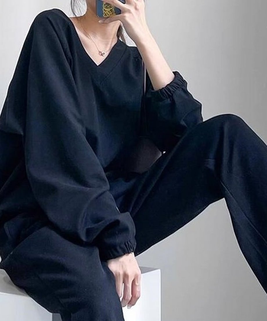 ブラックのVネックショートスウェットと黒のパンツを合わせた女性が座っている姿のクローズアップ。
