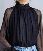 黒のドット柄シアーブラウスをデニムにインしたスタイルの上半身。フリル付きのハイネックとランタンスリーブが特徴。