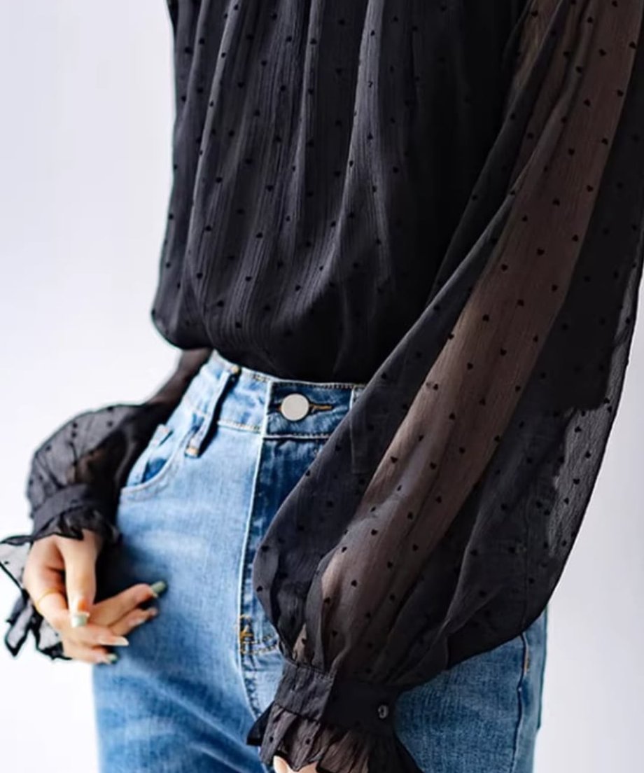 黒のドット柄シアーブラウスのランタンスリーブと、フリルカフスのクローズアップ。ハイウエストデニムを着用。