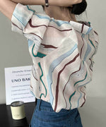 マーブル柄シアーシャツをデニムにインし、後ろ姿を見せている女性のバストアップ。