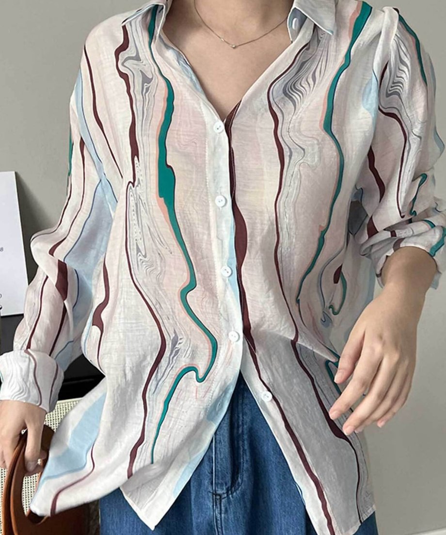 マーブル柄シアーシャツをデニムにタックインし、ボタンを数個開けて着用した上半身のクローズアップ。
