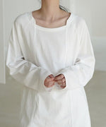 ホワイトのロングスリーブTシャツを着用した女性のバストアップ。首元はラウンドネックの上部にスクエア風の切込みがあり、前身頃中央に縦の切り替えディテールがある。