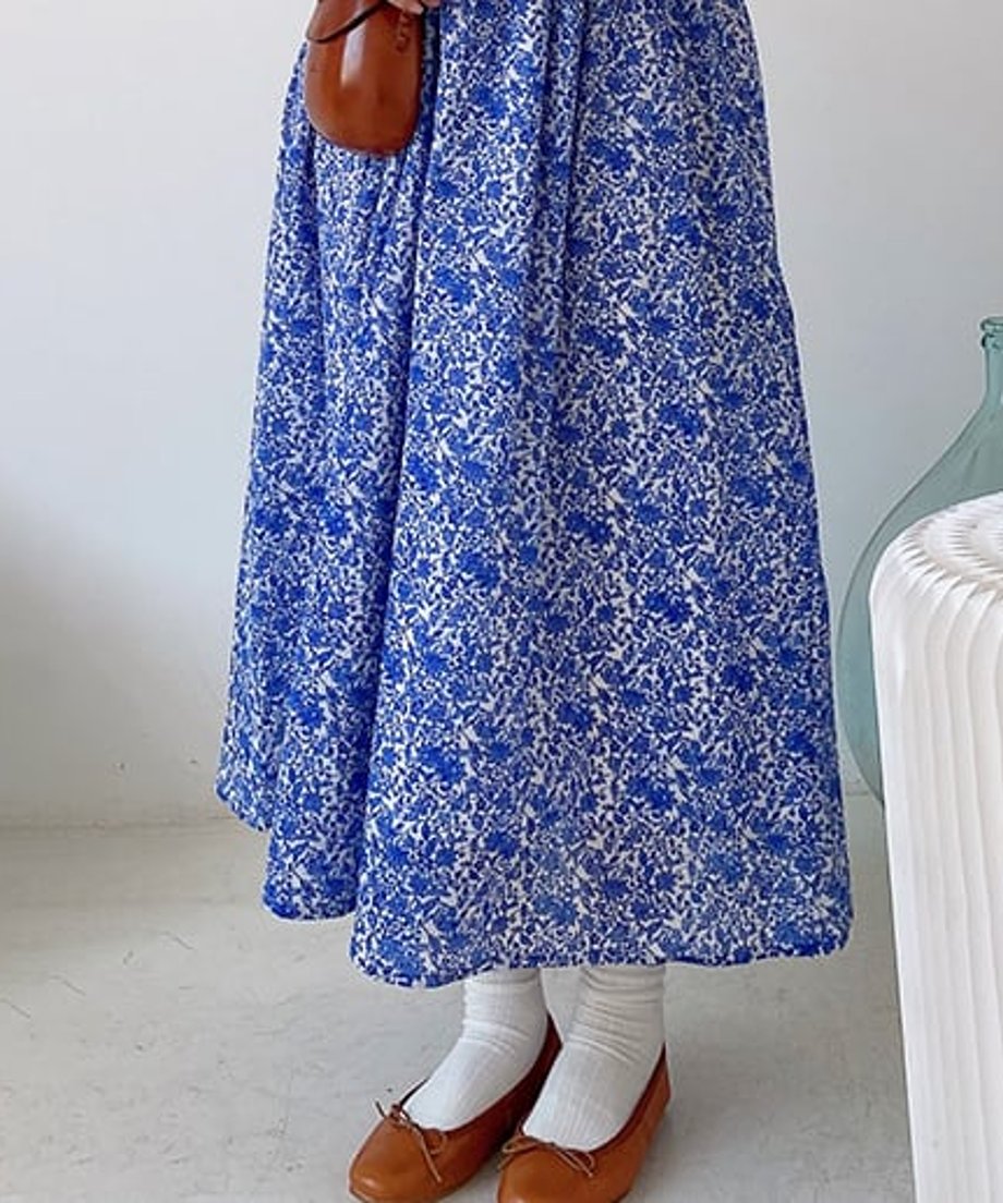 ブルーの小花柄ロングワンピースを着た女性の下半身。白いソックスとブラウンのバレーシューズを履いている。