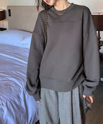 グレーのオーバーサイズスウェットを着用した女性の室内ショット。