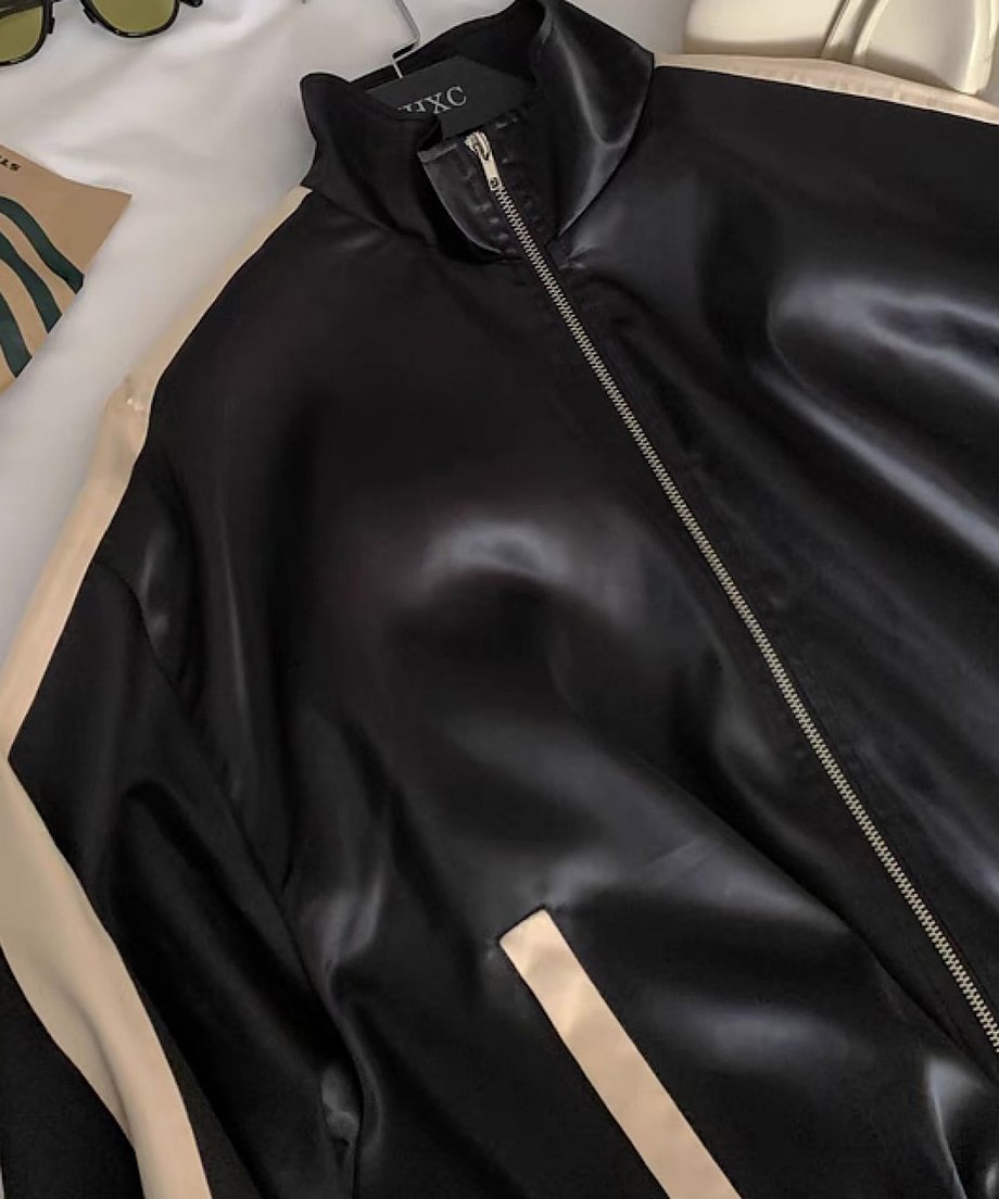 黒のバイカラーブルゾンのネックからじジップ部分にかけての静止画像。肩やポケットのバイカラーのデザインがわかる。