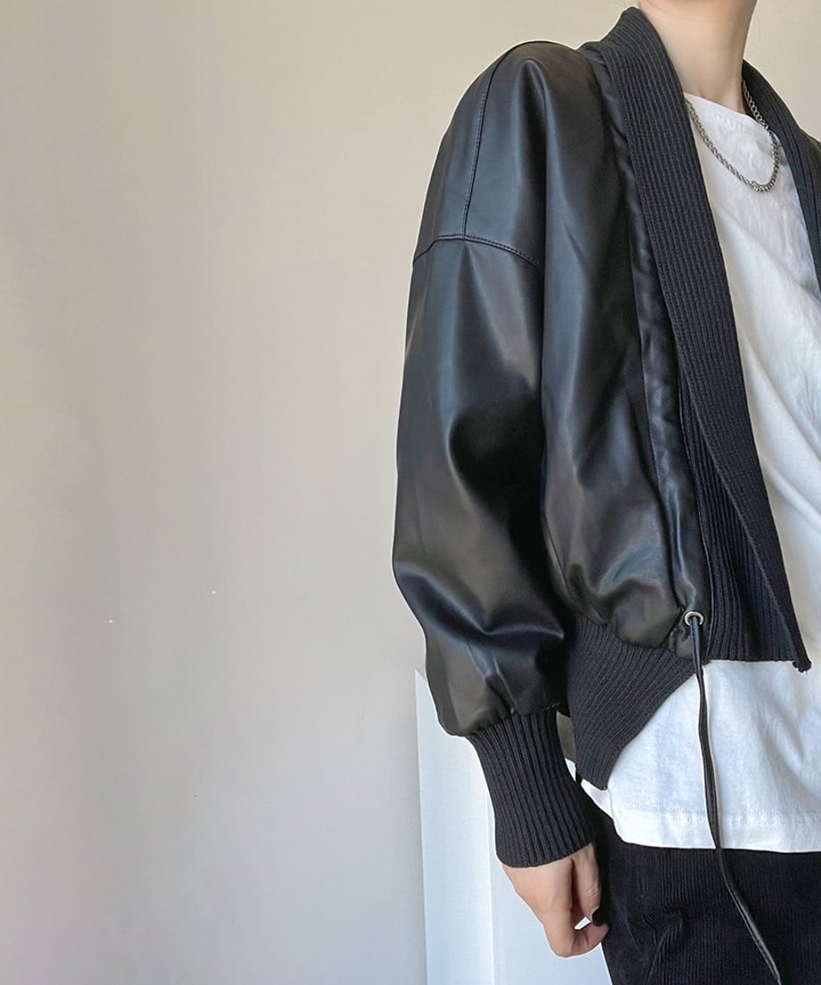黒のジャケットを着用した女性の横からのショット。身頃はレザー調素材、袖口と裾は幅広のリブニット。