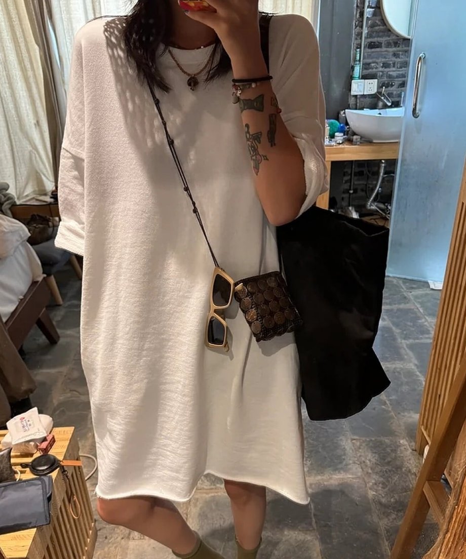 ホワイトのオーバーサイズワンピースを着用した女性が、室内でポーズをとっている全身ショット。
