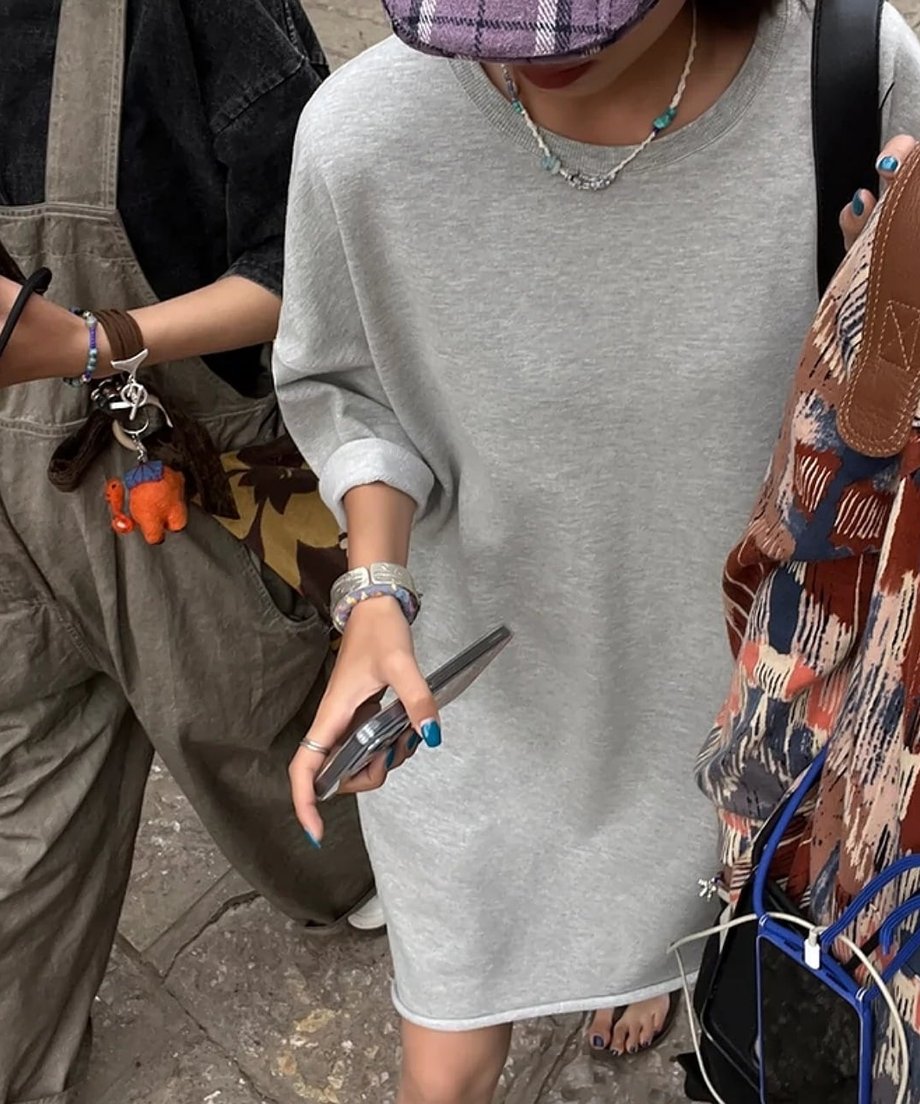 グレーのワンピースを着た女性が、友人と歩いている様子。ワンピースの切りっぱなしの裾が確認できる。
