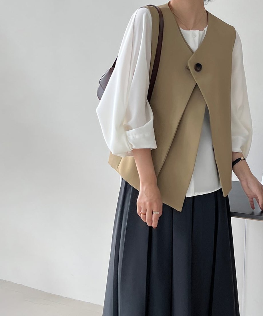 ベージュのベストを着た女性のクローズアップ。室内の黒いデスクのそばに手を置いたショット。