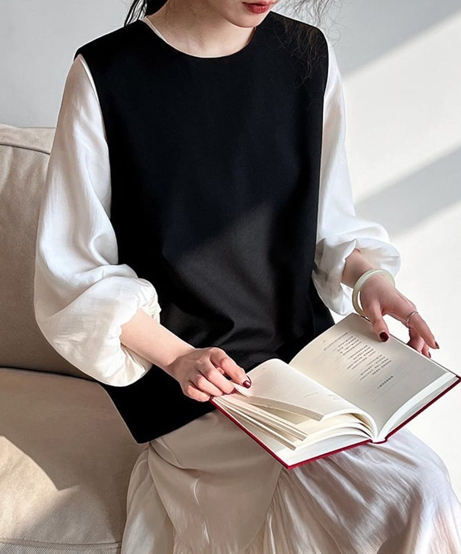 読書をするシーンでのブラックベストと白トップスのレイヤードコーディネート