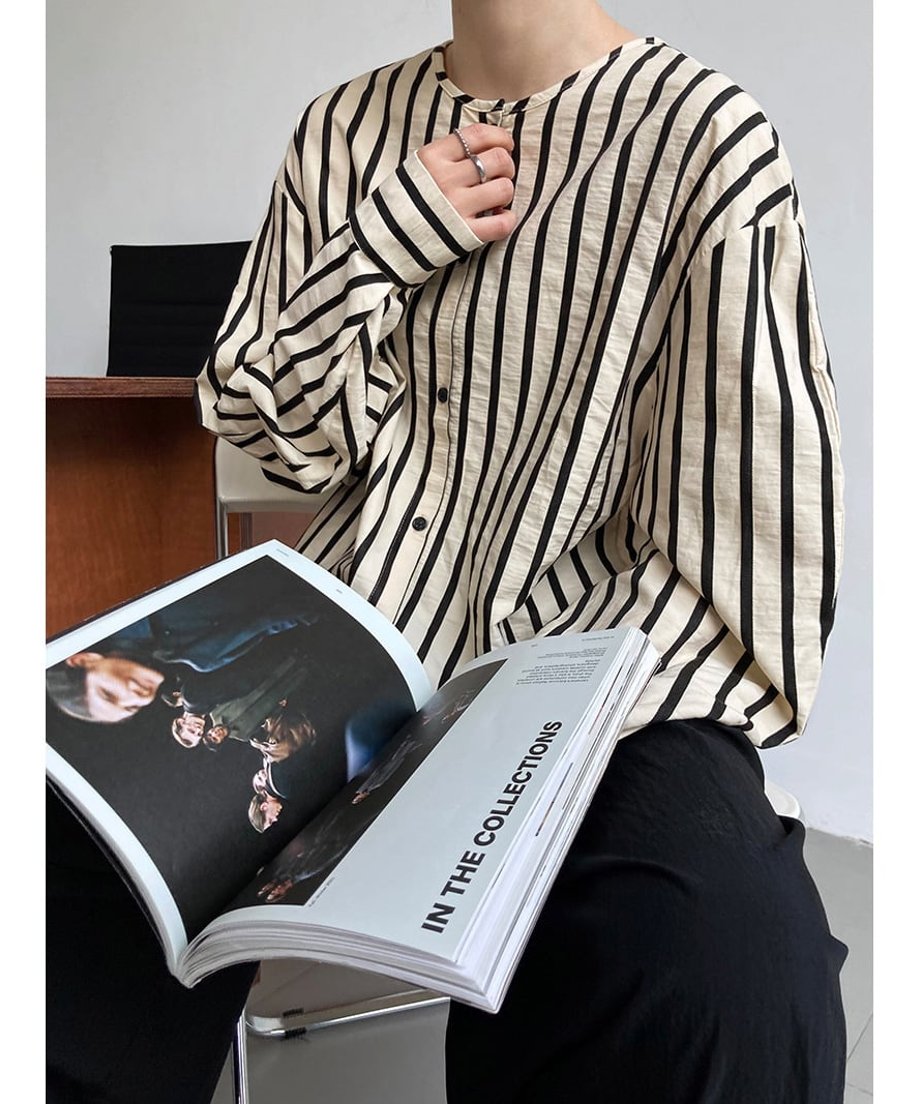 雑誌を膝上で広げて座っているストライプシャツ着用のモデルと生地の質感がわかるショット。