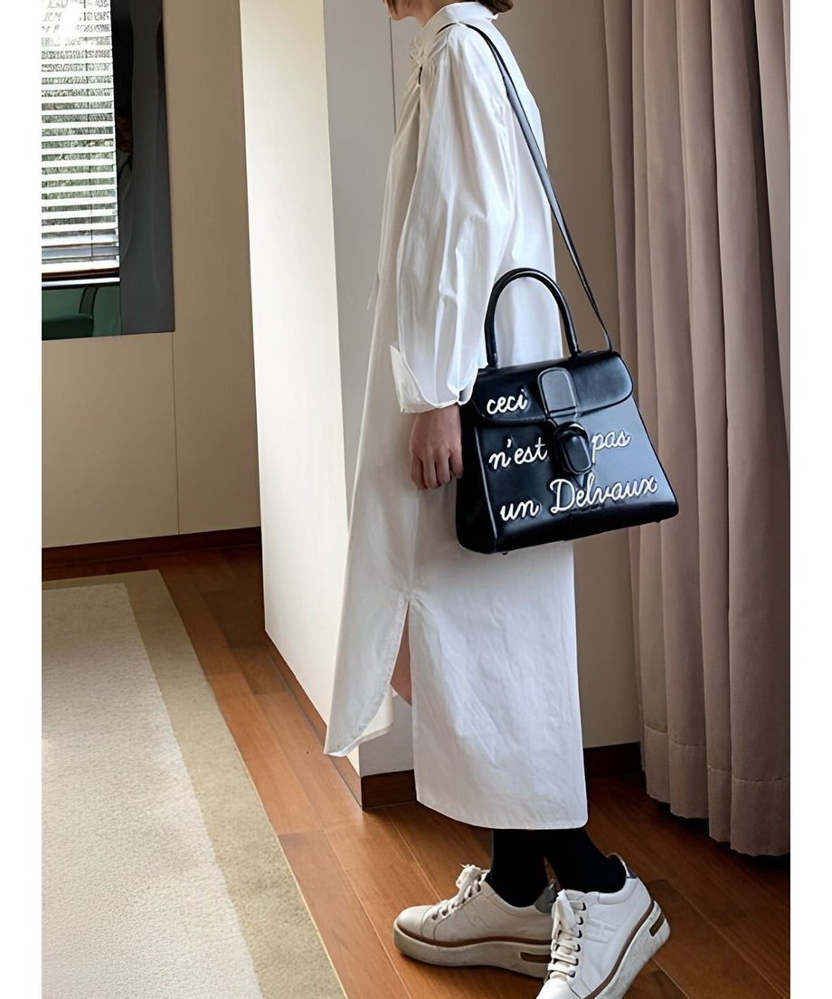 テールカットの裾とサイドスリットが際立つ、シャツドレスを着用した女性の斜め後ろからのカット。