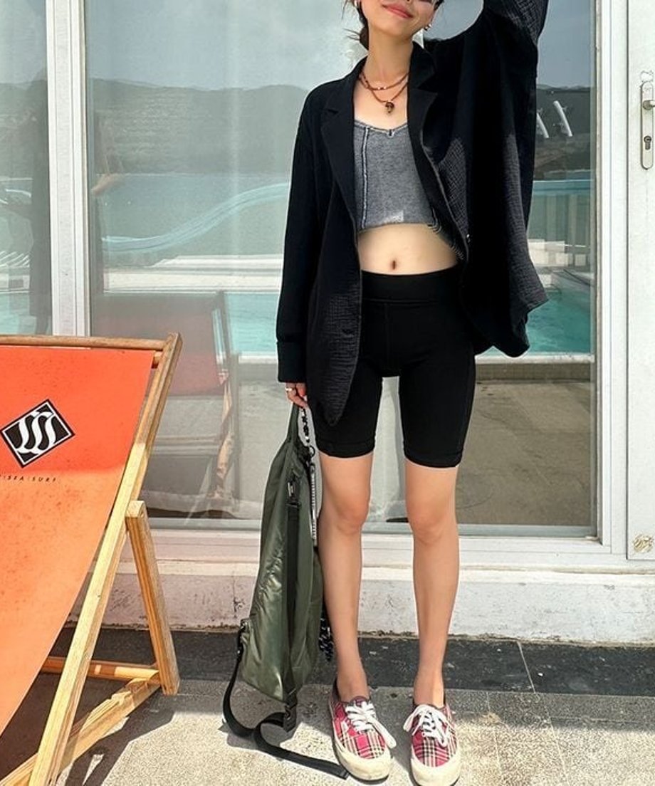 海辺に立つ女性のブラックのルーズジャケットにチェック柄スニーカーを合わせた、都会的なモノトーンコーデ。
