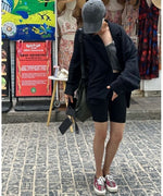 異国情緒ある街並みの中で、黒のハットと黒のジャケットを合わせた、大人っぽい夏の旅行スタイル。