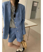 ブルーのセットアップを着用した女性のショット。タック入りのバミューダパンツとジャケットのボタンが４つ並んだデザインがわかる。