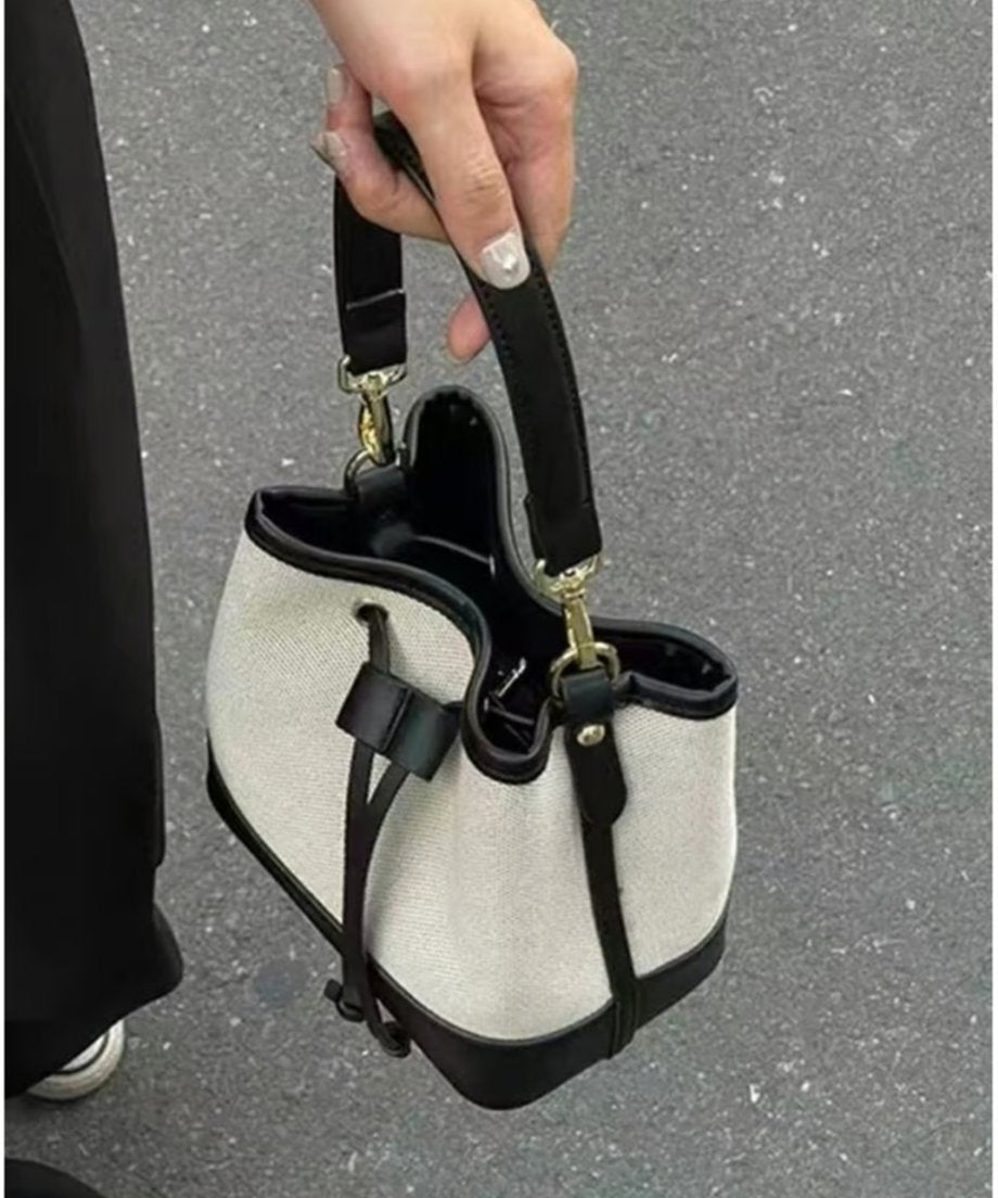手に持った状態のバイカラーバケットバッグを上から撮影した、内側の黒い裏地やファスナーポケットが確認できる詳細写真