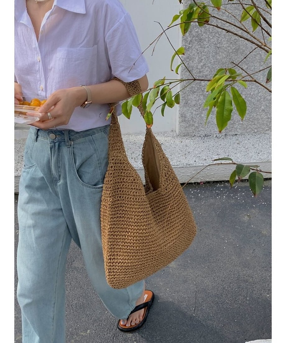 ストローバッグを持って歩く、白シャツとデニムの夏らしいコーディネート。