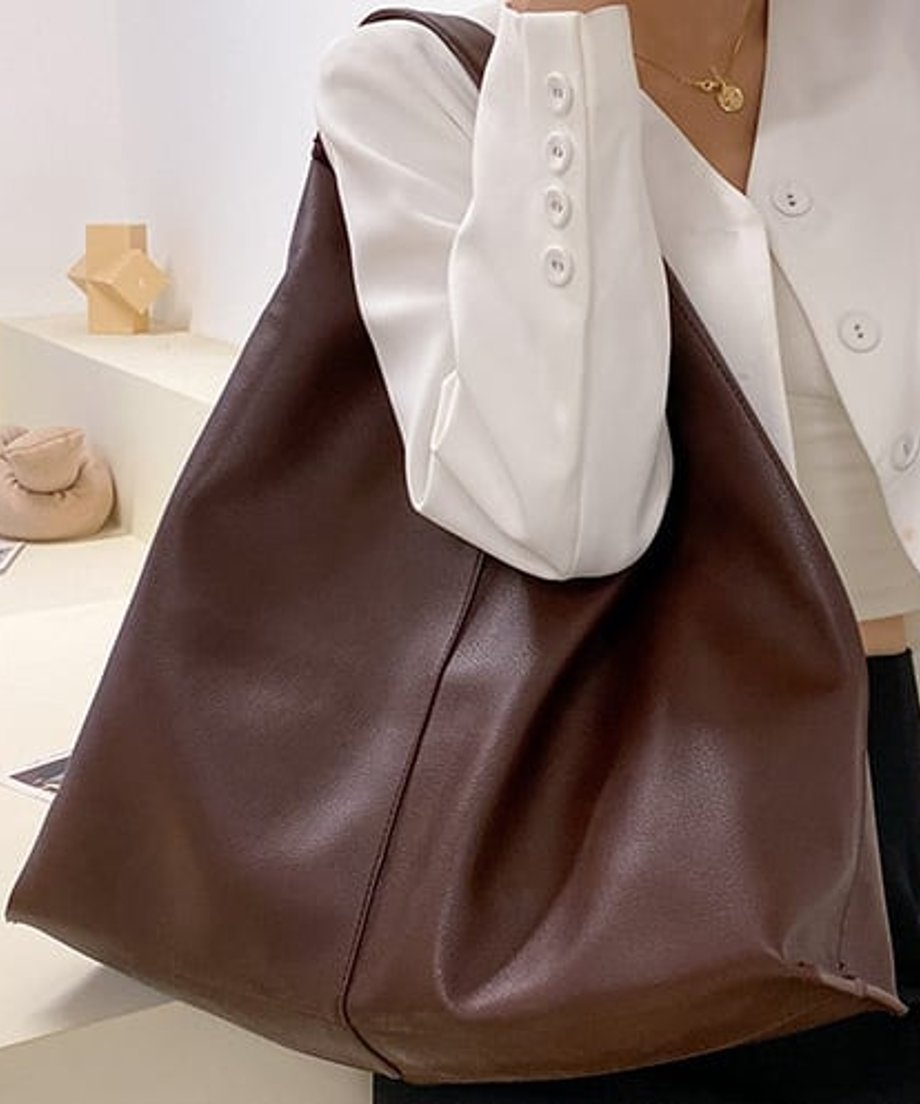 肩にかけた、柔らかい質感のブラウンの大きなフェイクレザーショルダーバッグ