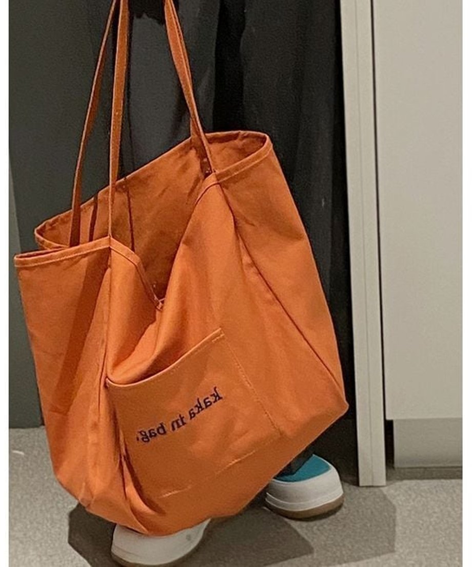 オレンジ色のトートバッグを手に下げたアップショット。