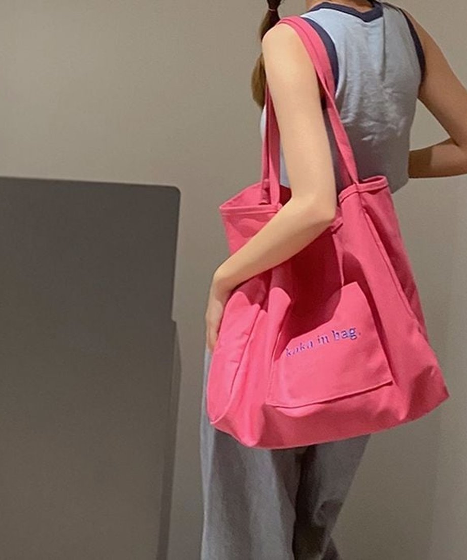 鮮やかなピンク色のロゴ入りビッグトートバッグを掛けた女性のバックショット。