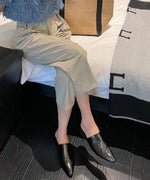 ベージュのパンツにブラックのミュールを合わせた、シックでミニマルな足元のアップ。