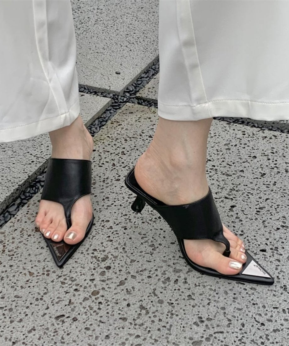 ブラックのレザー調サンダルを履き、白いパンツを合わせたクールな立ち姿の足元