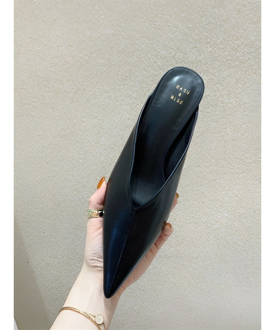手に持ったブラックのポインテッドトゥミュール。内側にはゴールドのロゴ入り。
